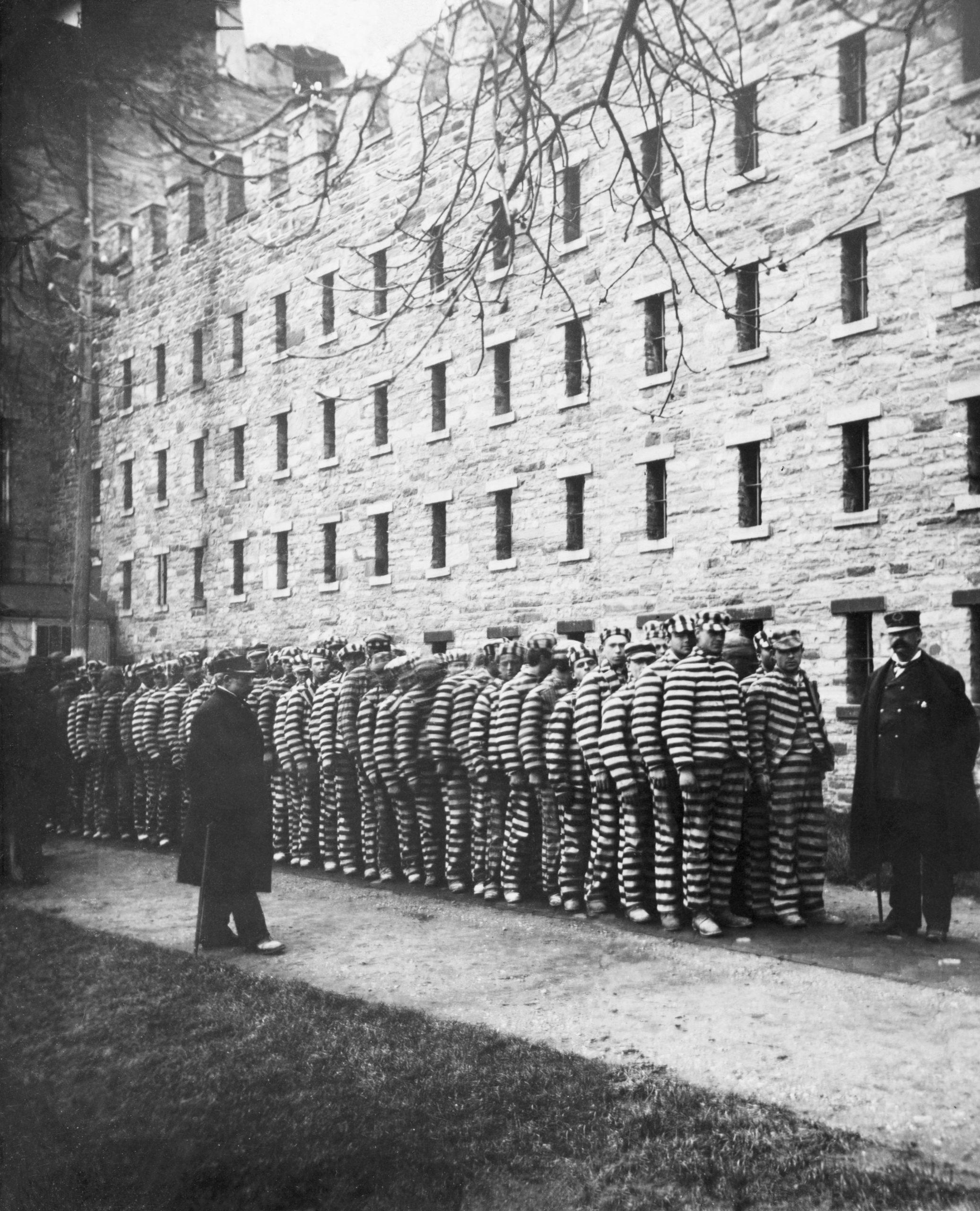 Prisoners lined up in their striped uniforms in yard of Sing Sing Prison.