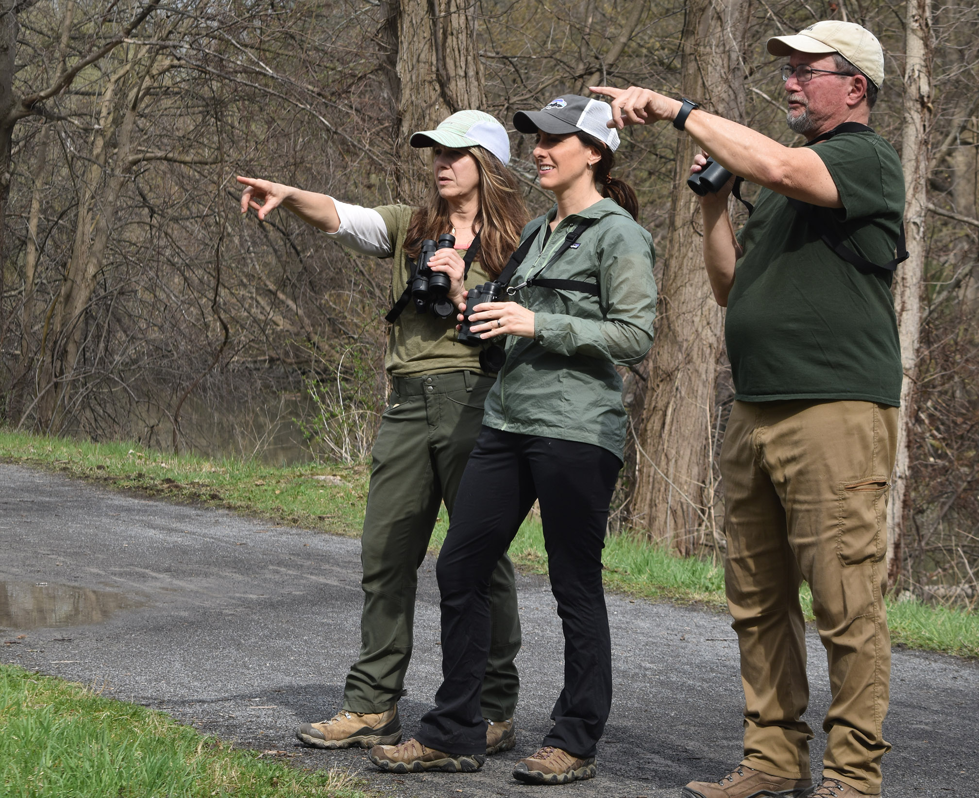 Wendy Kurlowicz , Danielle Davignon and Steve Kinane point toward birds along the Erie Canal during a birding expedition.